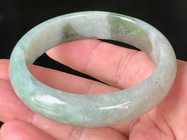 Close-up of fine crystalline texture and apple green hues on icy greyish white jadeite bangle