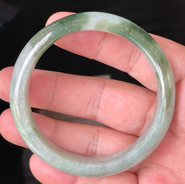 Close-up of fine crystalline texture and apple green hues on icy greyish white jadeite bangle
