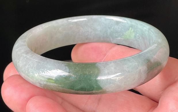 Close-up of fine crystalline texture and apple green hues on icy greyish white jadeite bangle