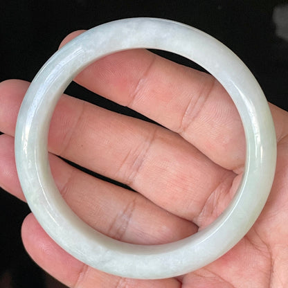 Close-up of fine crystalline texture and delicate apple green hues on icy greyish white jadeite bangle
