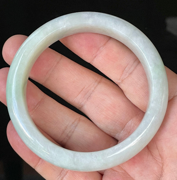 Close-up of fine crystalline texture and delicate apple green hues on icy greyish white jadeite bangle