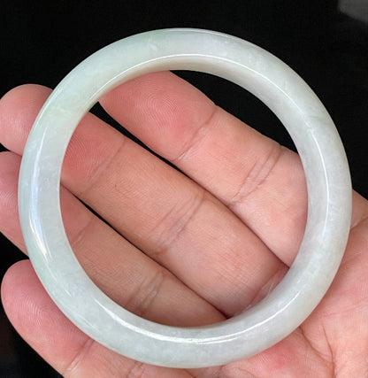 Close-up of fine crystalline texture and delicate apple green hues on icy greyish white jadeite bangle