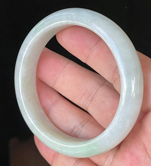 Close-up of fine crystalline texture and delicate apple green hues on icy greyish white jadeite bangle