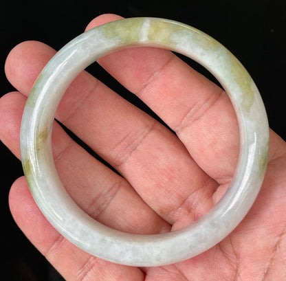 Close-up of fine crystalline texture and apple green patterns on icy greyish white jadeite bangle