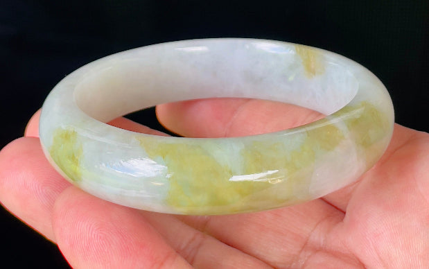 Close-up of fine crystalline texture and apple green patterns on icy greyish white jadeite bangle