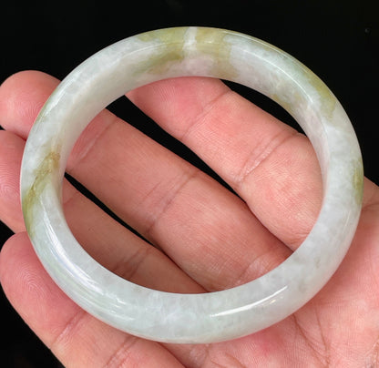 Close-up of fine crystalline texture and apple green patterns on icy greyish white jadeite bangle