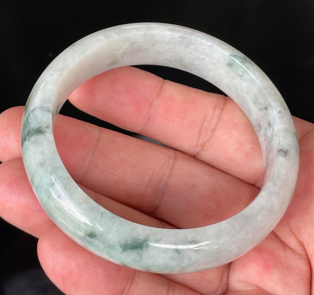 Close-up of fine crystalline texture and moss in the snow effect on greyish milky white and green jadeite bangle