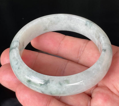 Close-up of fine crystalline texture and moss in the snow effect on greyish milky white and green jadeite bangle