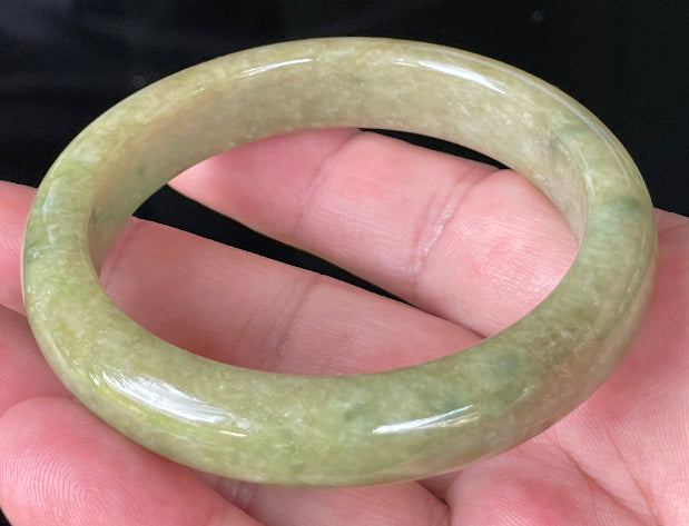 Close-up of fine crystalline texture and honey brown hues on icy green jadeite bangle