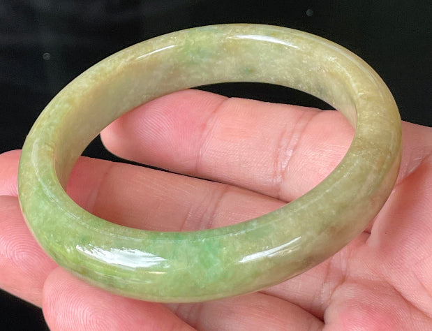 Close-up of fine crystalline texture and honey brown hues on icy green jadeite bangle