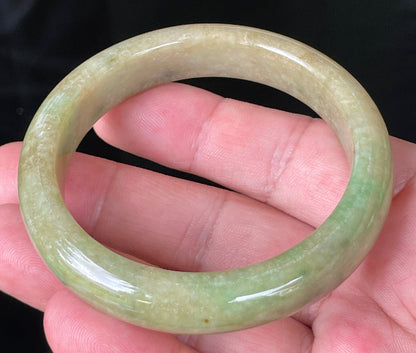 Close-up of fine crystalline texture and honey brown hues on icy green jadeite bangle