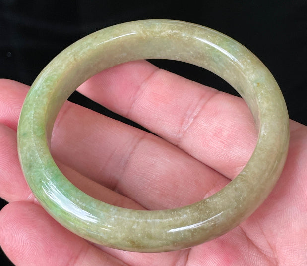 Close-up of fine crystalline texture and honey brown hues on icy green jadeite bangle