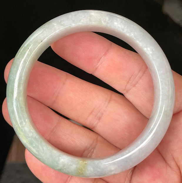 Close-up of fine crystalline texture and apple green hues on icy light lavender and white jadeite bangle