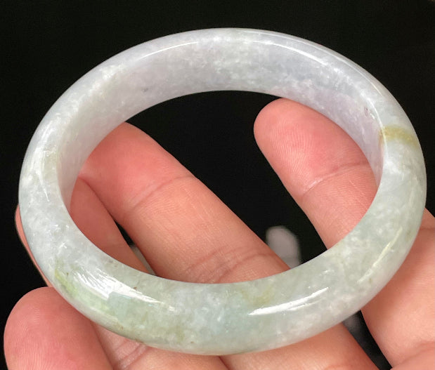 Close-up of fine crystalline texture and apple green hues on icy light lavender and white jadeite bangle