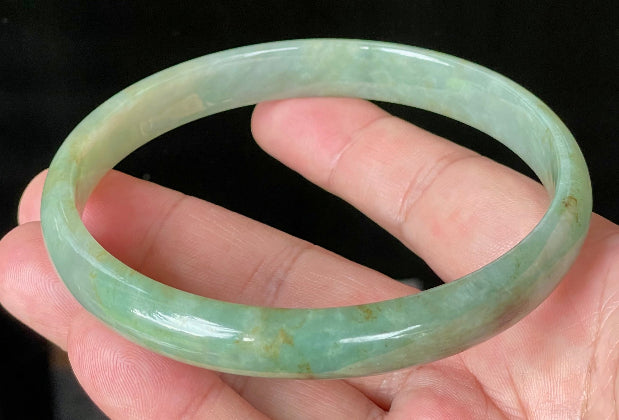 Close-up of fine crystalline texture and vivid imperial green hues on icy apple green jadeite bangle