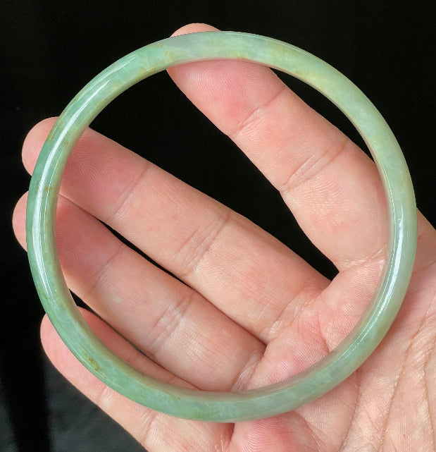 Close-up of fine crystalline texture and vivid imperial green hues on icy apple green jadeite bangle