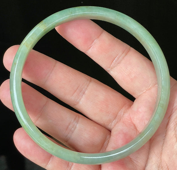 Close-up of fine crystalline texture and vivid imperial green hues on icy apple green jadeite bangle