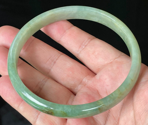 Close-up of fine crystalline texture and vivid imperial green hues on icy apple green jadeite bangle