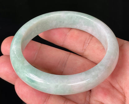 Close-up of fine crystalline texture and moss in the snow effect on icy milky white and green jadeite bangle
