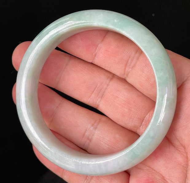 Close-up of fine crystalline texture and moss in the snow effect on icy milky white and green jadeite bangle