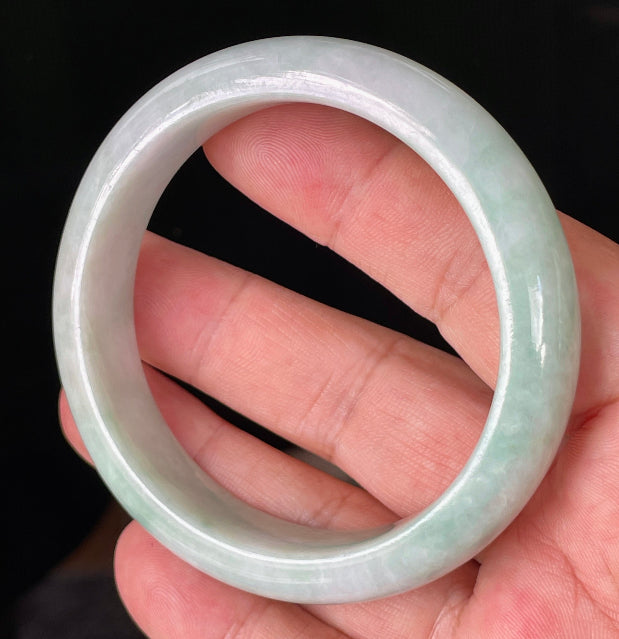 Close-up of fine crystalline texture and moss in the snow effect on icy milky white and green jadeite bangle