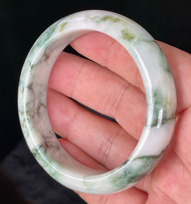 Close-up of fine crystalline texture and moss in the snow effect on icy milky white and green jadeite bangle