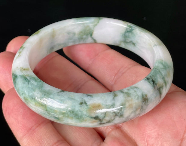 Close-up of fine crystalline texture and moss in the snow effect on icy milky white and green jadeite bangle