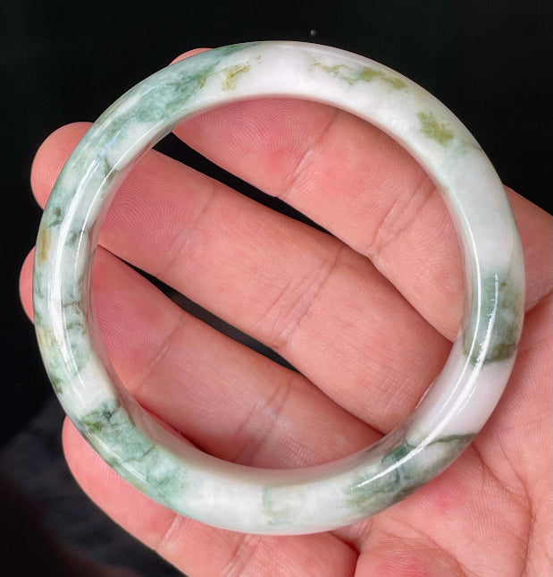 Close-up of fine crystalline texture and moss in the snow effect on icy milky white and green jadeite bangle