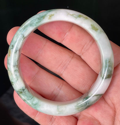 Close-up of fine crystalline texture and moss in the snow effect on icy milky white and green jadeite bangle