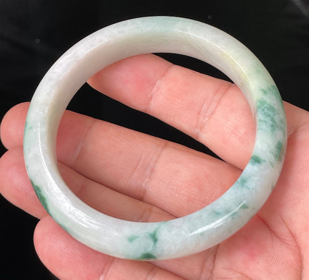 Close-up of fine crystalline texture and vibrant imperial green hues on icy milky white jadeite bangle