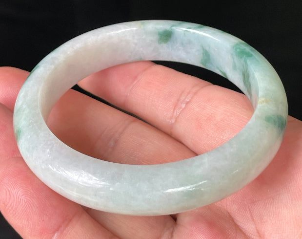 Close-up of fine crystalline texture and vibrant imperial green hues on icy milky white jadeite bangle