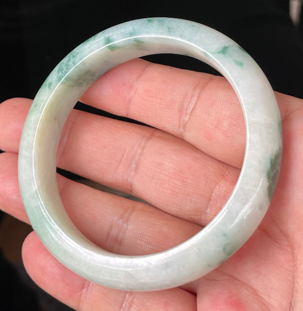 Close-up of fine crystalline texture and vibrant imperial green hues on icy milky white jadeite bangle