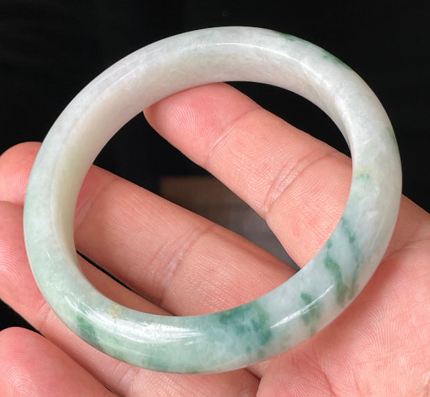 Close-up of fine crystalline texture and vibrant imperial green hues on icy milky white jadeite bangle
