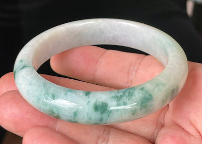 Close-up of fine crystalline texture and vibrant imperial green hues on icy milky white jadeite bangle