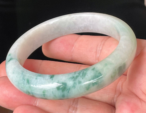 Close-up of fine crystalline texture and vibrant imperial green hues on icy milky white jadeite bangle