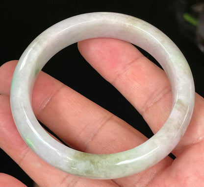 Close-up of fine crystalline texture and tranquil moss green hues on icy imperial green and white jadeite bangle