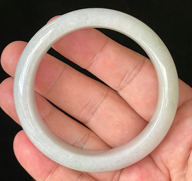 Close-up of fine crystalline texture and delicate light apple green hues on icy milky white jadeite bangle