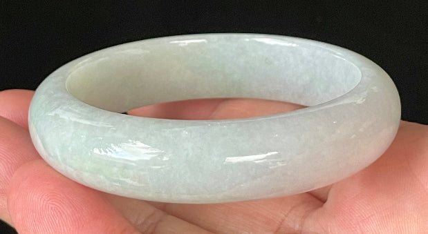Close-up of fine crystalline texture and delicate light apple green hues on icy milky white jadeite bangle