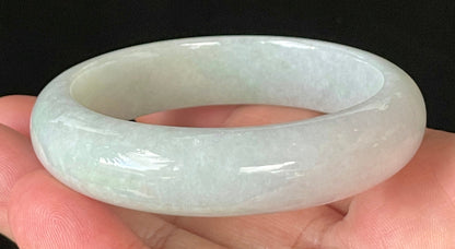Close-up of fine crystalline texture and delicate light apple green hues on icy milky white jadeite bangle