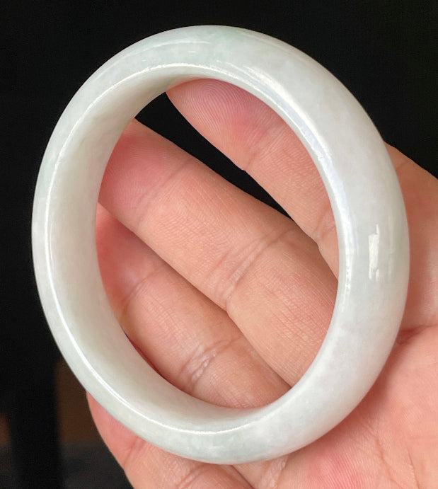 Close-up of fine crystalline texture and delicate apple green hues on icy milky white jadeite bangle