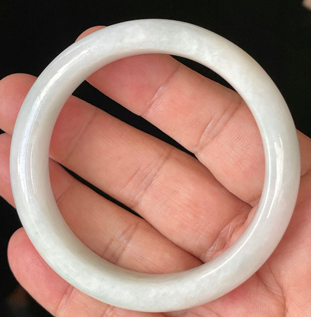 Close-up of fine crystalline texture and delicate apple green hues on icy milky white jadeite bangle