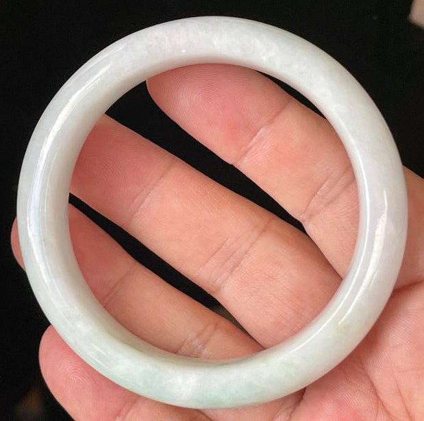 Close-up of fine crystalline texture and delicate apple green hues on icy milky white jadeite bangle