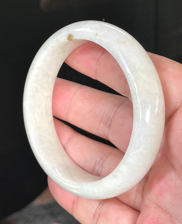 Close-up of fine crystalline texture and warm honey hues on icy milky white jadeite bangle