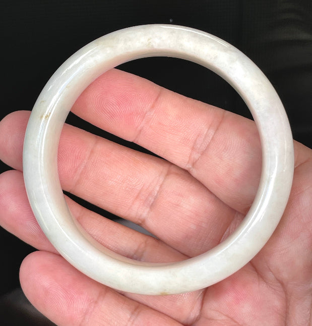 Close-up of fine crystalline texture and warm honey hues on icy milky white jadeite bangle