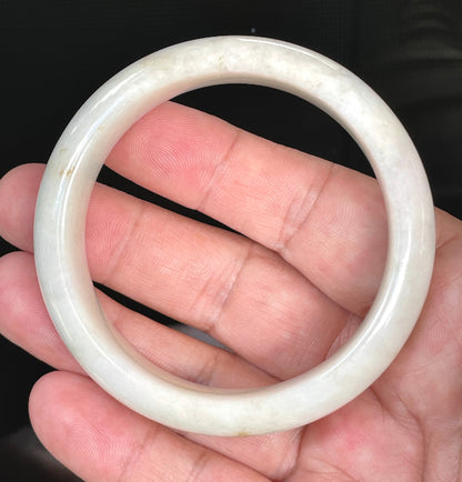 Close-up of fine crystalline texture and warm honey hues on icy milky white jadeite bangle