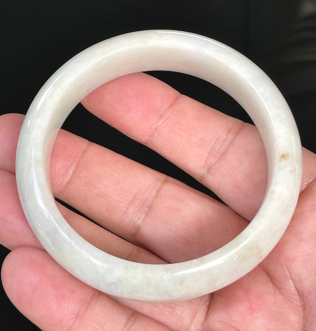 Close-up of fine crystalline texture and warm honey hues on icy milky white jadeite bangle