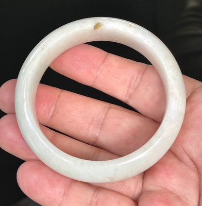 Close-up of fine crystalline texture and warm honey hues on icy milky white jadeite bangle