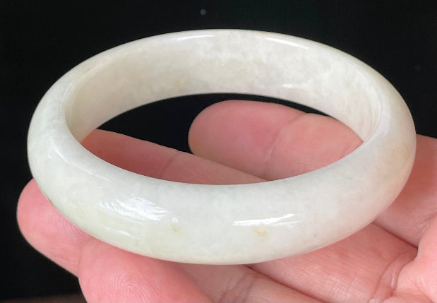 Close-up of fine crystalline texture and warm honey hues on icy milky white jadeite bangle