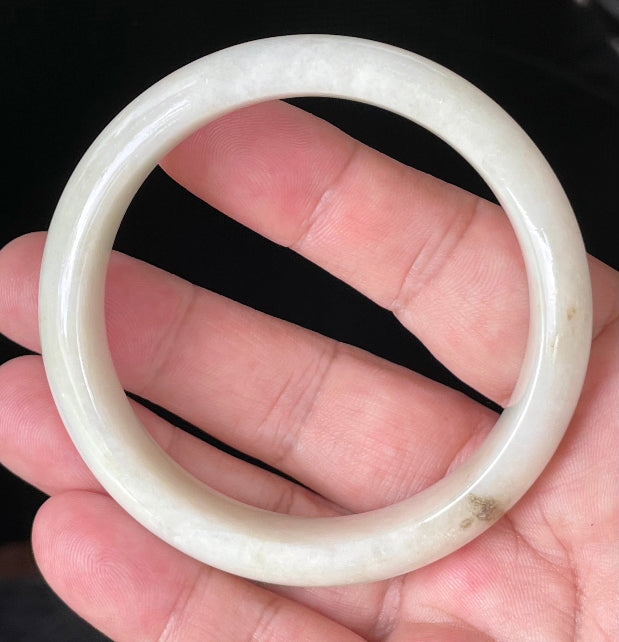 Close-up of fine crystalline texture and warm honey hues on icy milky white jadeite bangle