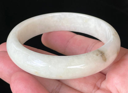 Close-up of fine crystalline texture and warm honey hues on icy milky white jadeite bangle